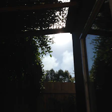 Sunlight filtering through sleek pergola shades over a wooden deck.