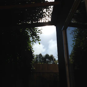 Sunlight filtering through sleek pergola shades over a wooden deck.