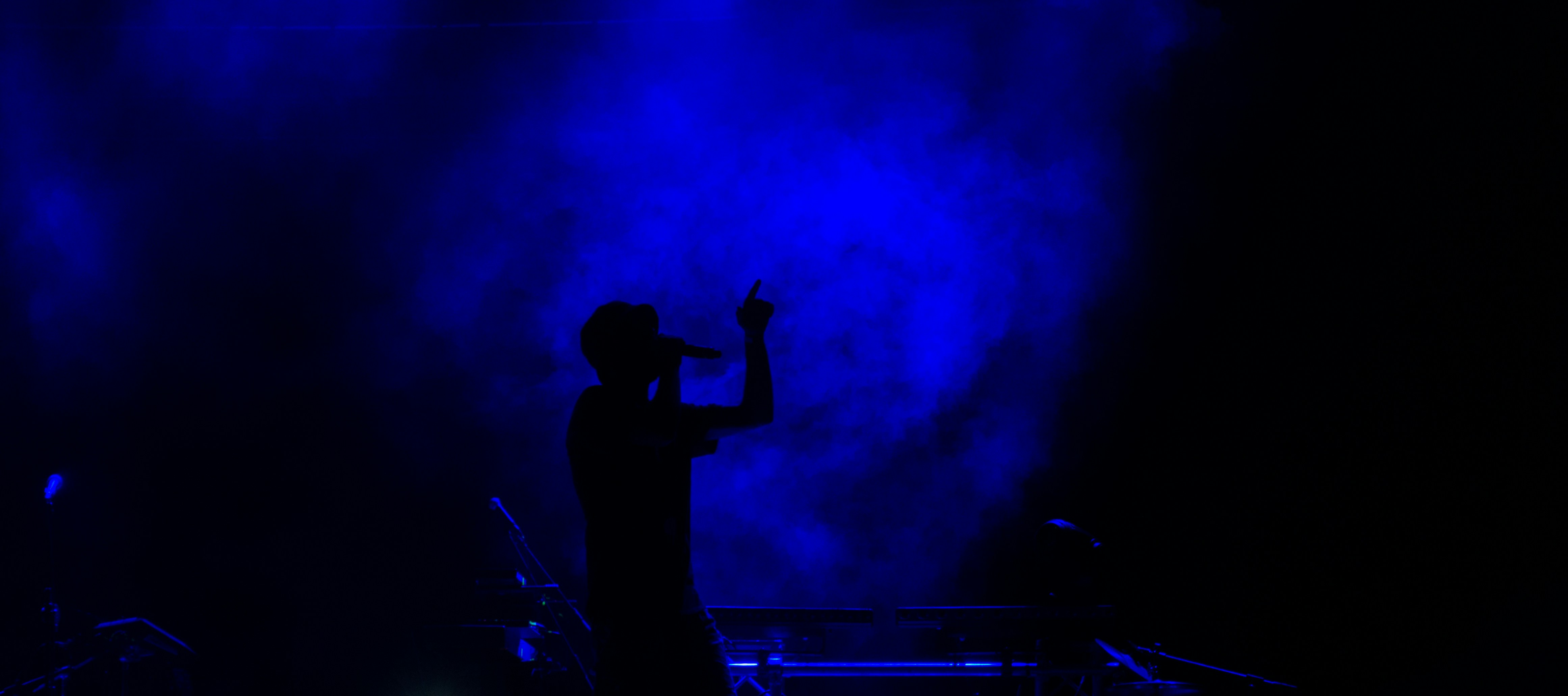 Female vocalist performing on stage with dramatic backlit silhouette and smoke effects