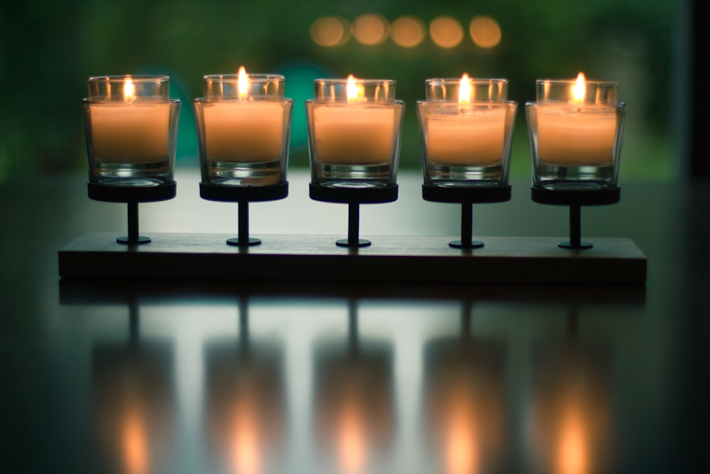 bokeh photography of five lighted votive candles