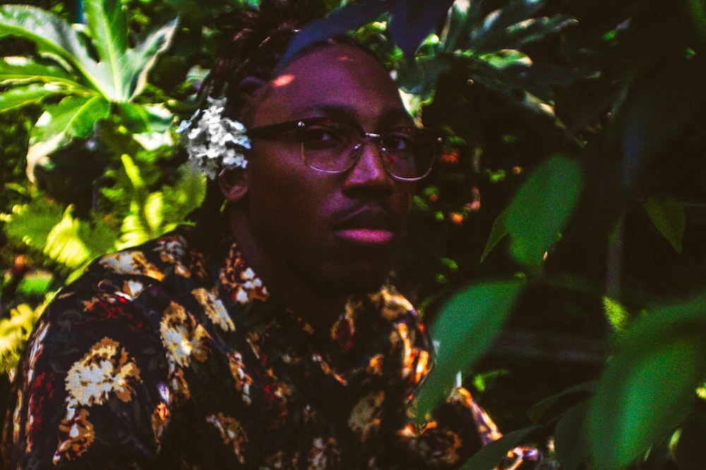 man wearing floral shirt taking photo under tree