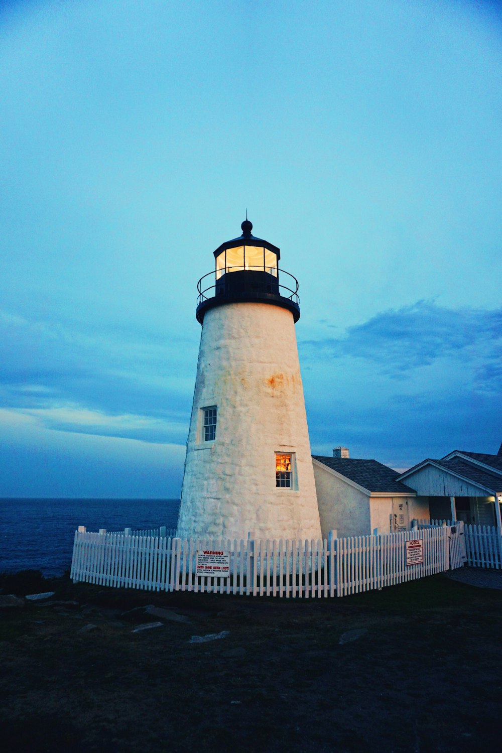 white and black lighthouse near body of water during daytime