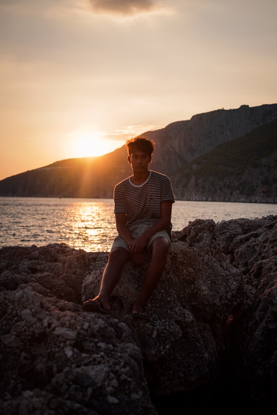 man sitting on rock near sea at golden hour in Brač Croatia