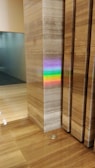 A polished marble wall and floor create a sleek and modern interior scene. A vibrant rainbow reflection appears on the marble surface, originating from an unseen light source. The colors of the rainbow stand out against the neutral tones of the marble.
