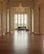 A spacious, elegantly decorated room featuring tall white columns and a glossy wooden floor. At the far end near tall windows with a view of greenery, there is a grand piano accompanied by a bench and a violin case. A chandelier hangs from the ceiling adding a touch of luxury to the setting.