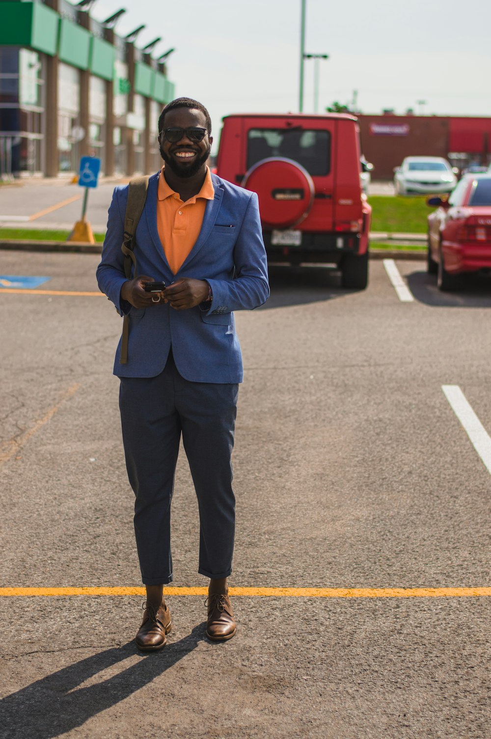 man in blue suit jacket standing at the back of red car