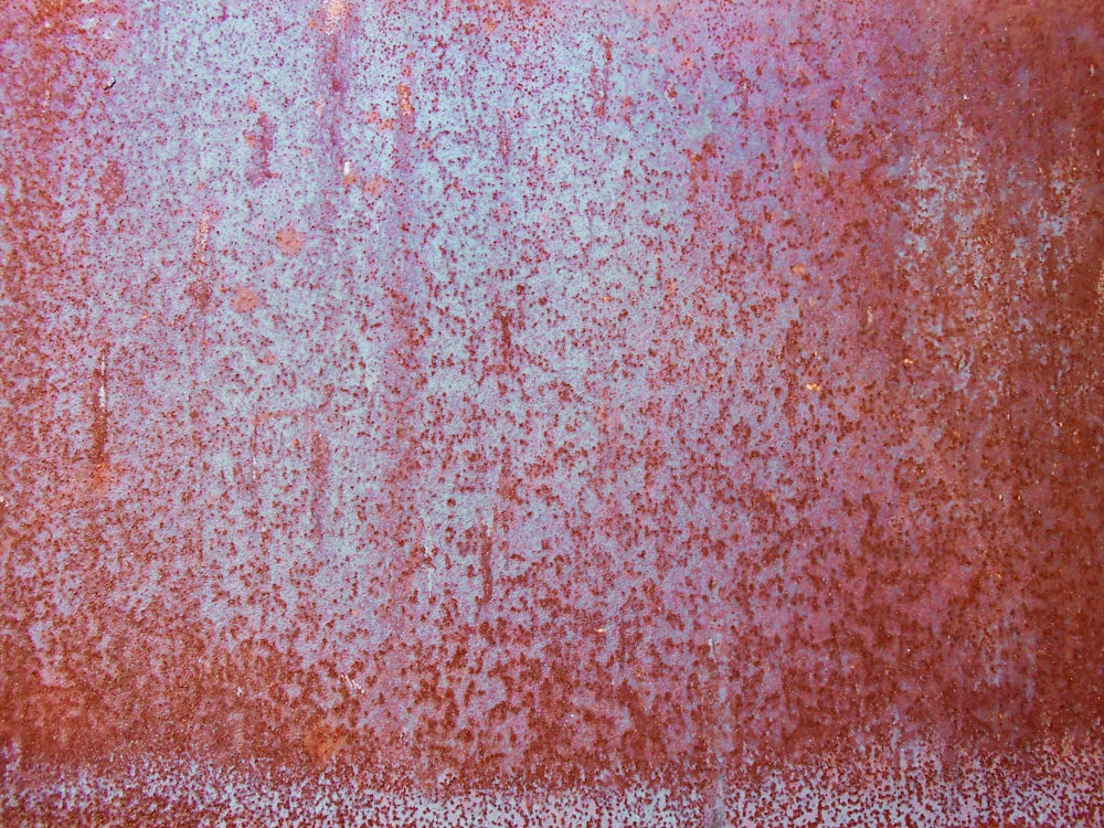 una superficie metallica arrugginita con sfondo rosso