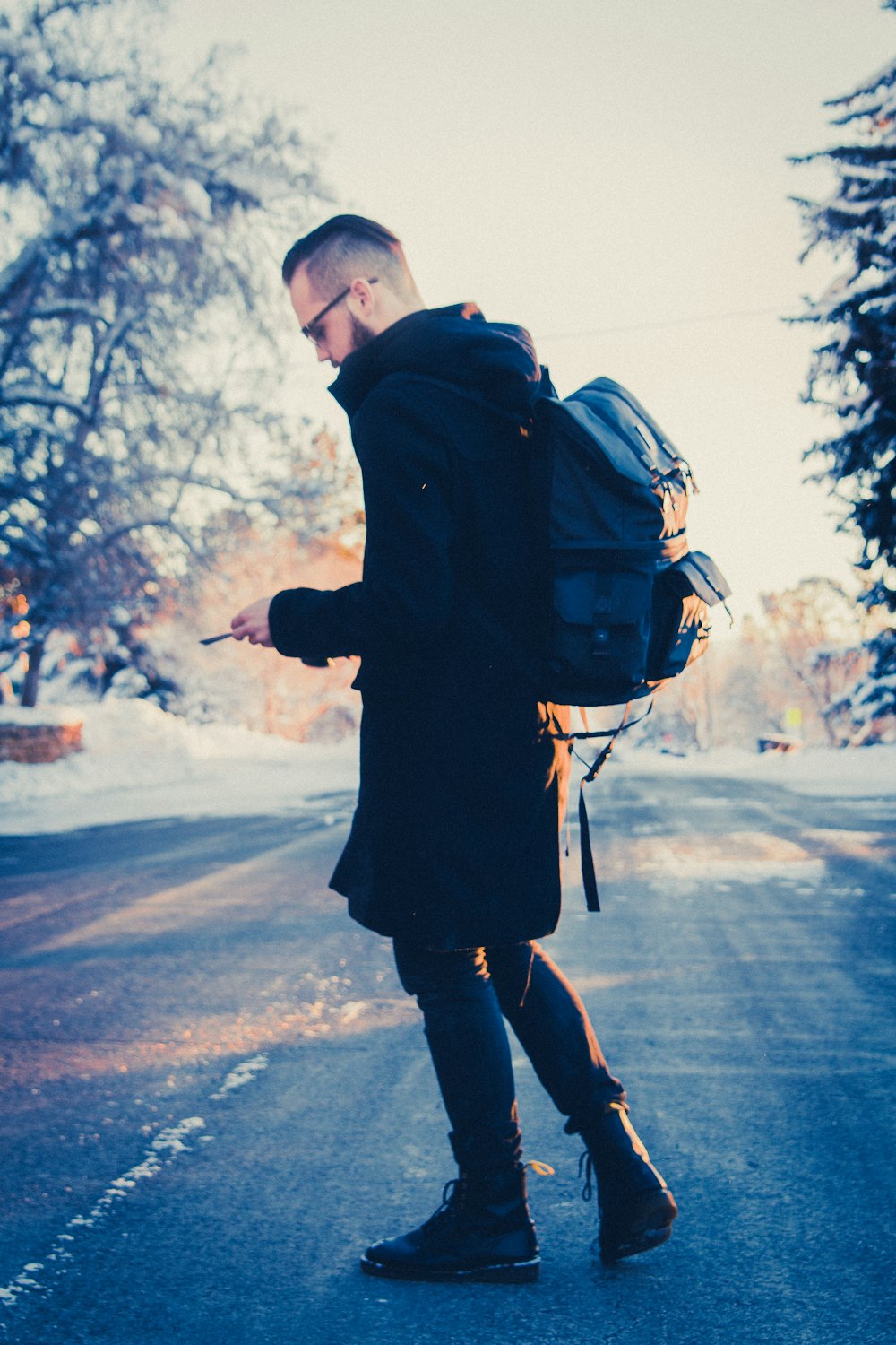 selective focus photography of man in black coat carrying gray backpack