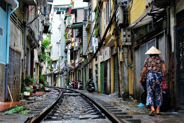 Person walking on railway side between buildings at daytime — Hanoi, Vietnam