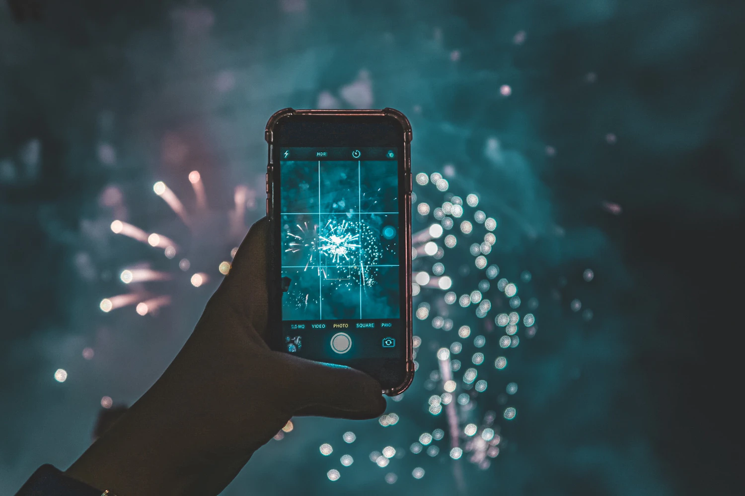 Bracing a phone against a railing and locking focus and exposure on the first burst gives far cleaner fireworks shots than hand-holding on auto.