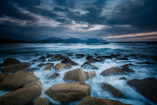 brown rocks on seashore during daytime in Dinas Dinlle United Kingdom