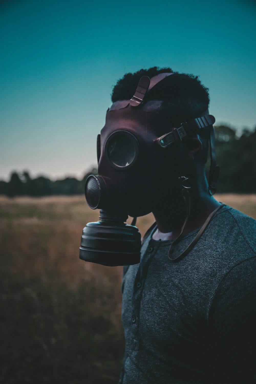 man wearing brown gas mask standing on brown field