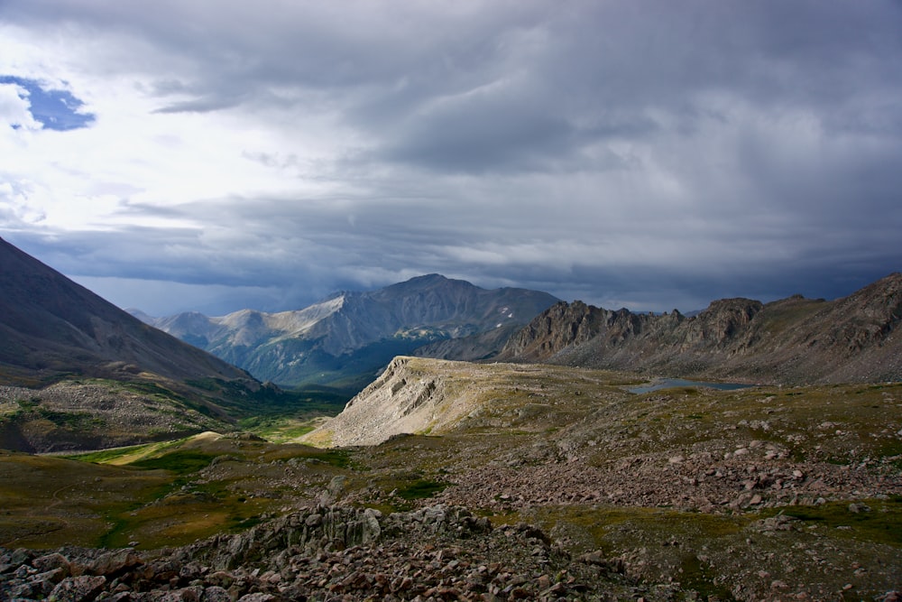 montagnes vertes et grises sous un ciel nuageux