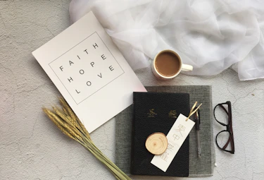 An artfully arranged flat lay of inspirational apparel and delicate jewelry against a backdrop of handwritten scripture.