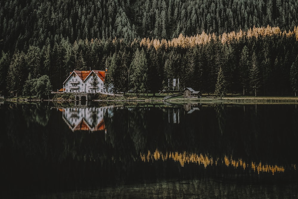 Casa branca e marrom com reflexo na água cercada de árvores