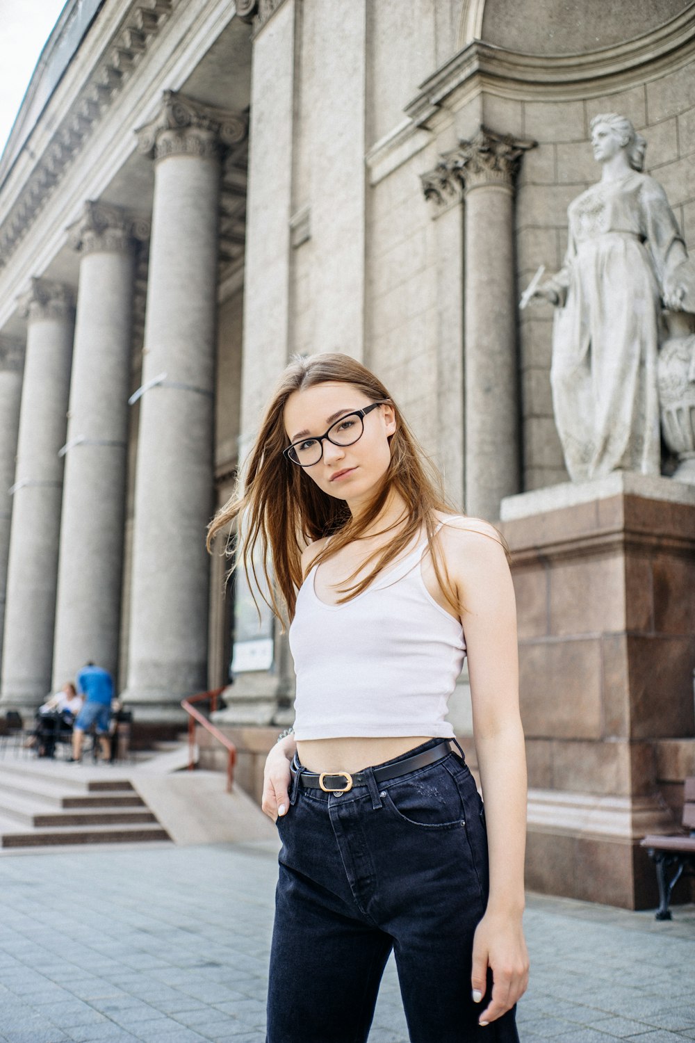 woman wearing white tank top standing near statue