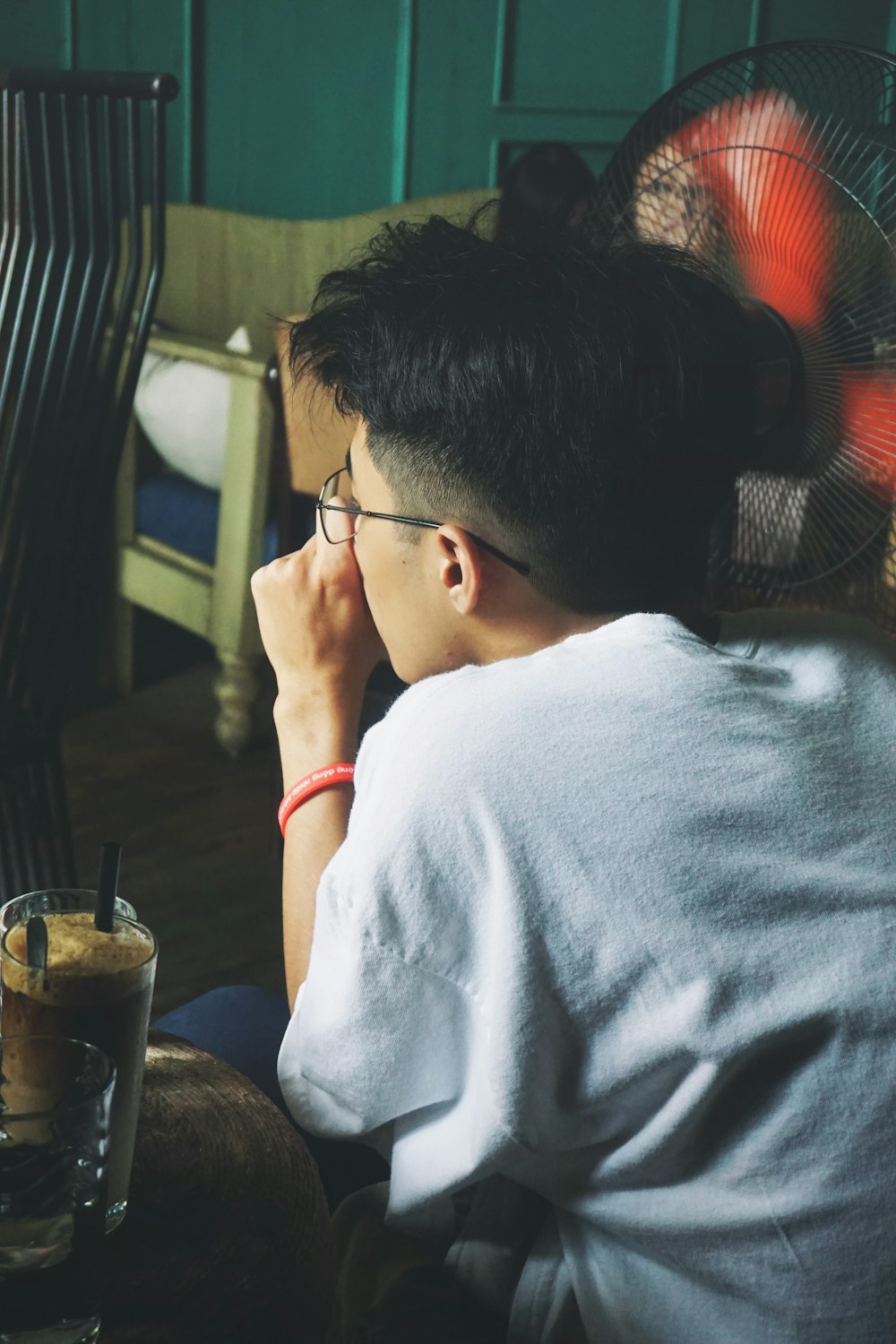 man seating beside fan