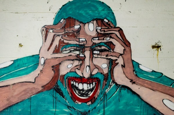 a stylized mural (with some dripping back paint) of a man grasping his head in pain