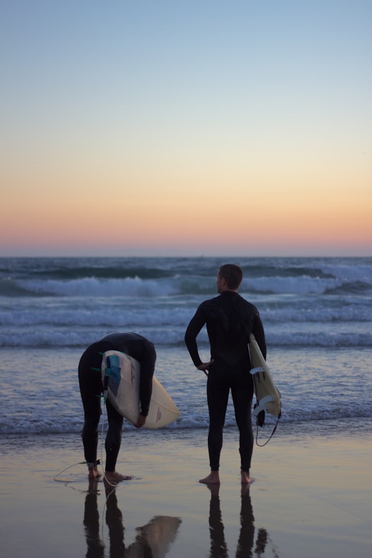 two person in black wetsuit holding surfboards standing on beach in Newport Beach United States