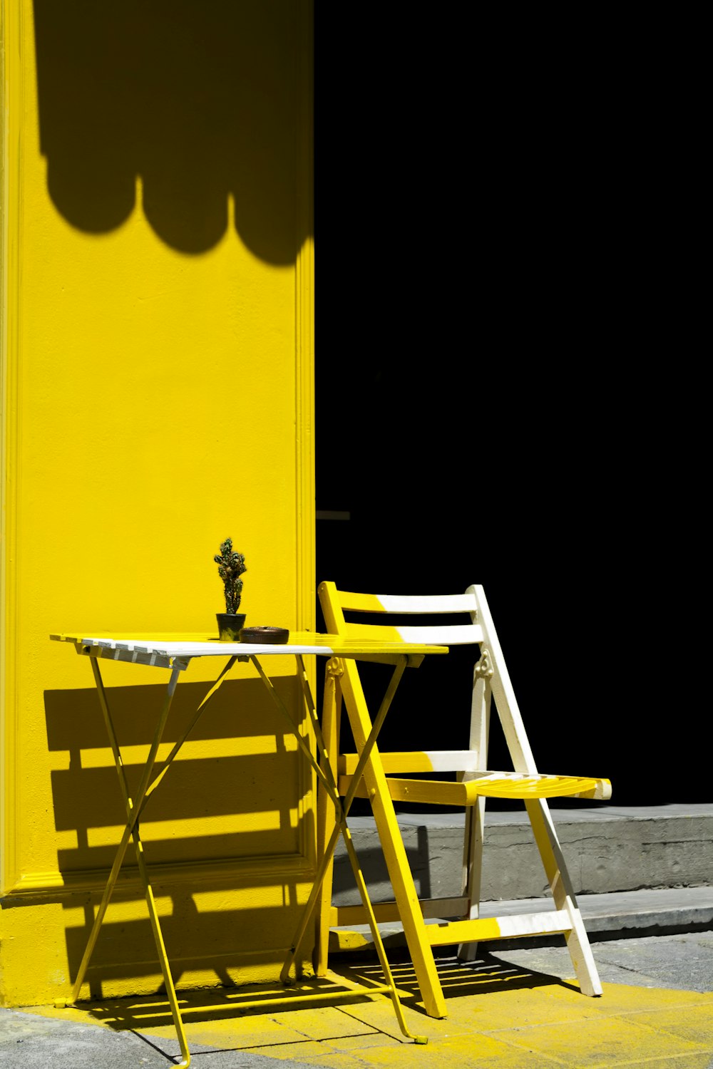 노란색 벽 근처의 접이식 테이블과 의자