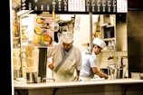 Chefs preparing Indian roti canai and Japanese cuisine in a busy commercial kitchen.