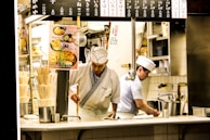 Hospitality professionals from Africa serving guests in a Japanese restaurant.