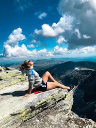 woman sitting on peak of mountain