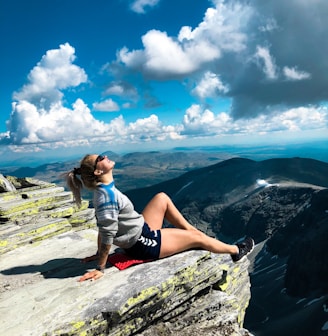 woman sitting on peak of mountain