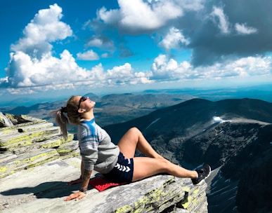 woman sitting on peak of mountain