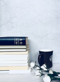 An inviting flat lay of signed books stacked beside a journal and a motivational mug on a bright, colorful background.