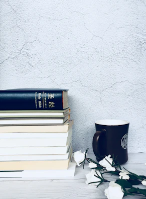 Books arranged alongside a gold champagne-accented coffee mug.