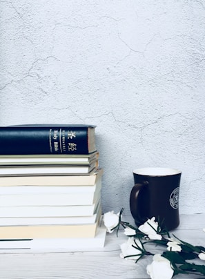 A neat arrangement of finance books with a pink coffee mug beside them.