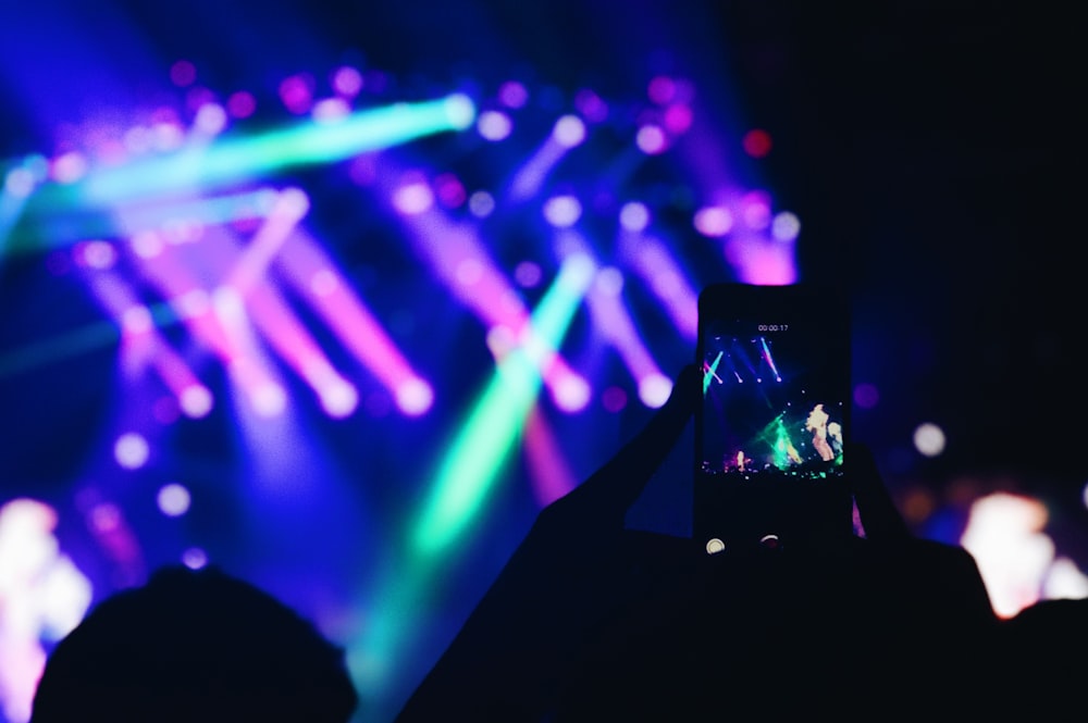 person taking photo of concert