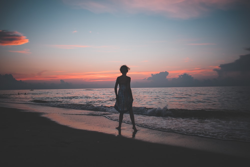 ゴールデンアワーの海岸に立つ女性