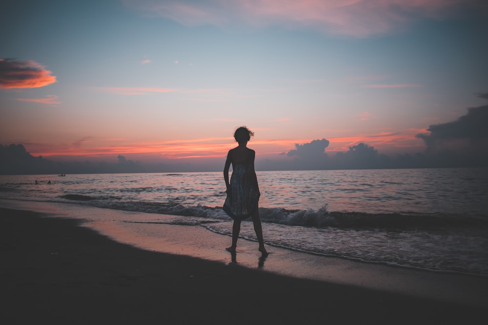 woman standing on the seashore during golden hour