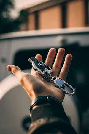 A driver receiving car keys outside a vehicle, representing the license and registration errands handled at a DMV office