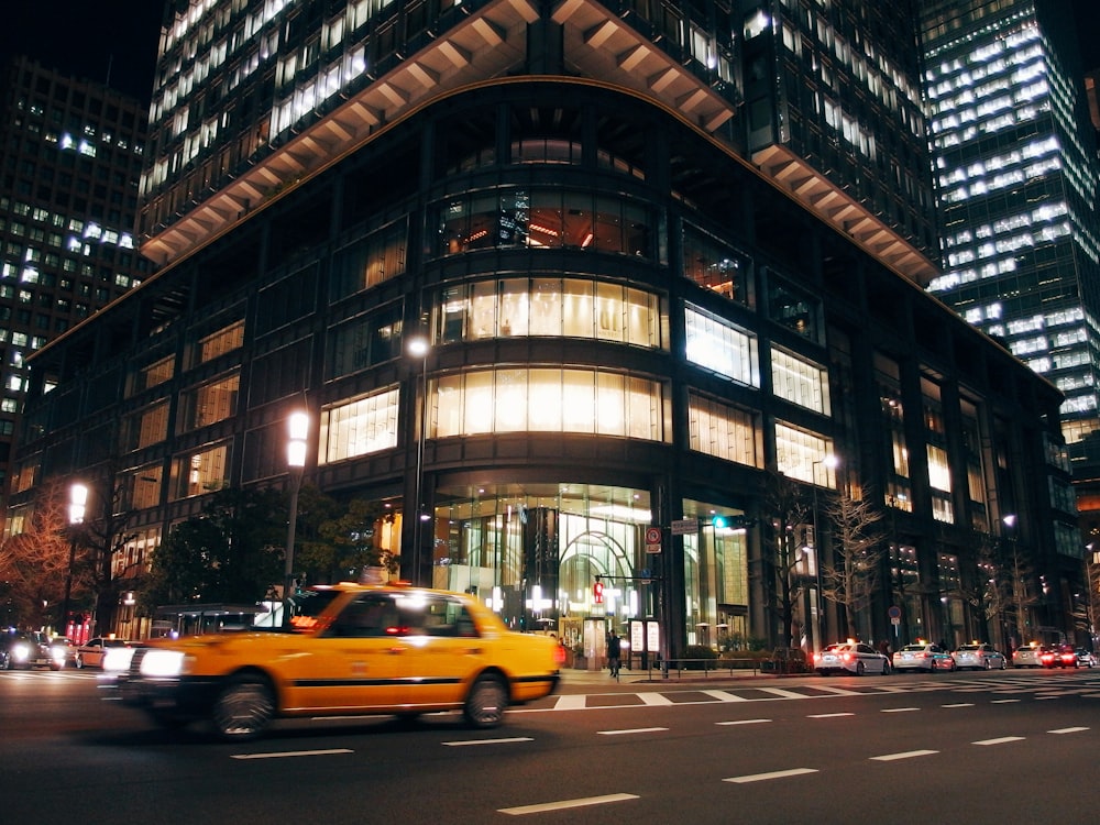 time lapse photography of yellow taxi sedan near building