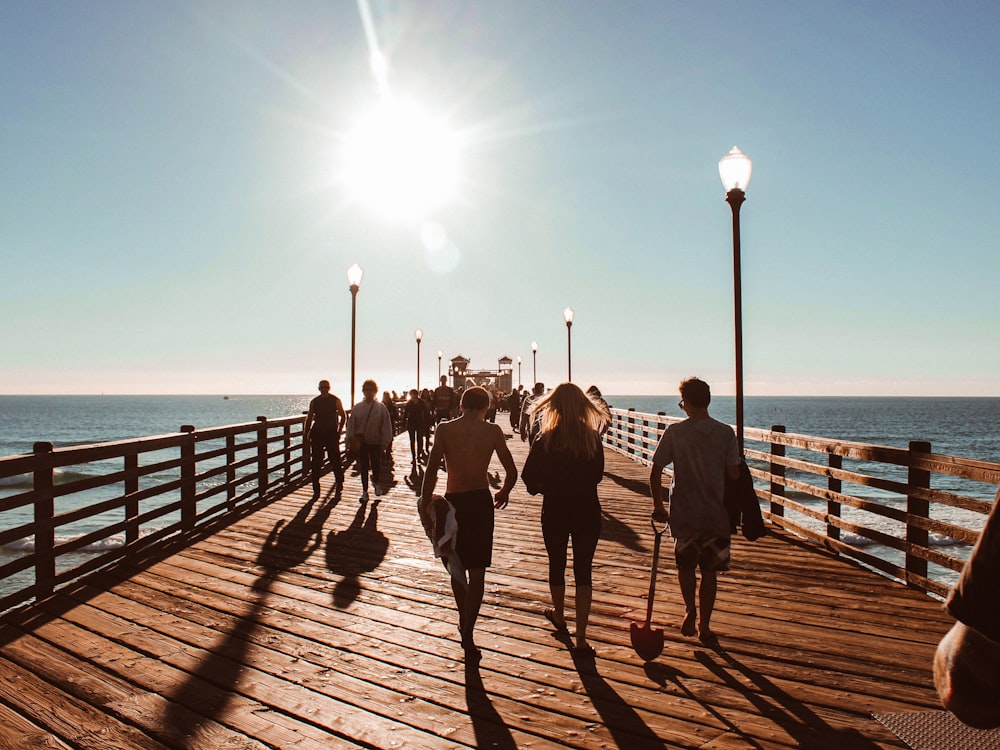 people walking towards on brown wooden dock