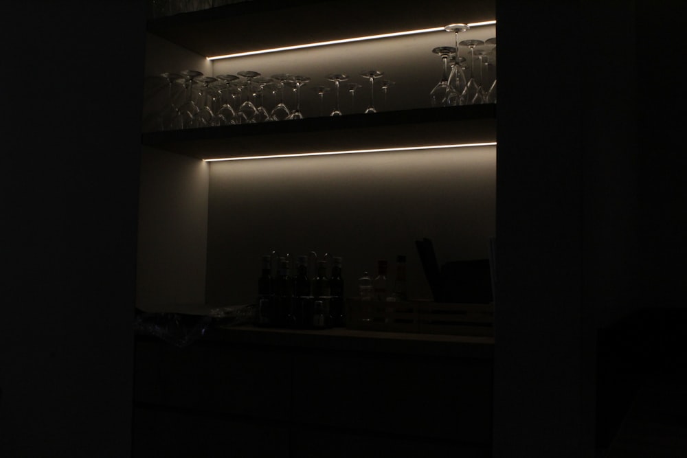 a dark room with a shelf filled with bottles and glasses