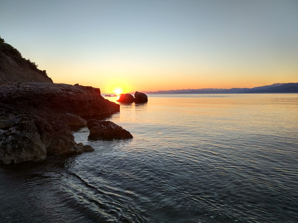 body of water hitting rocks during golden hour