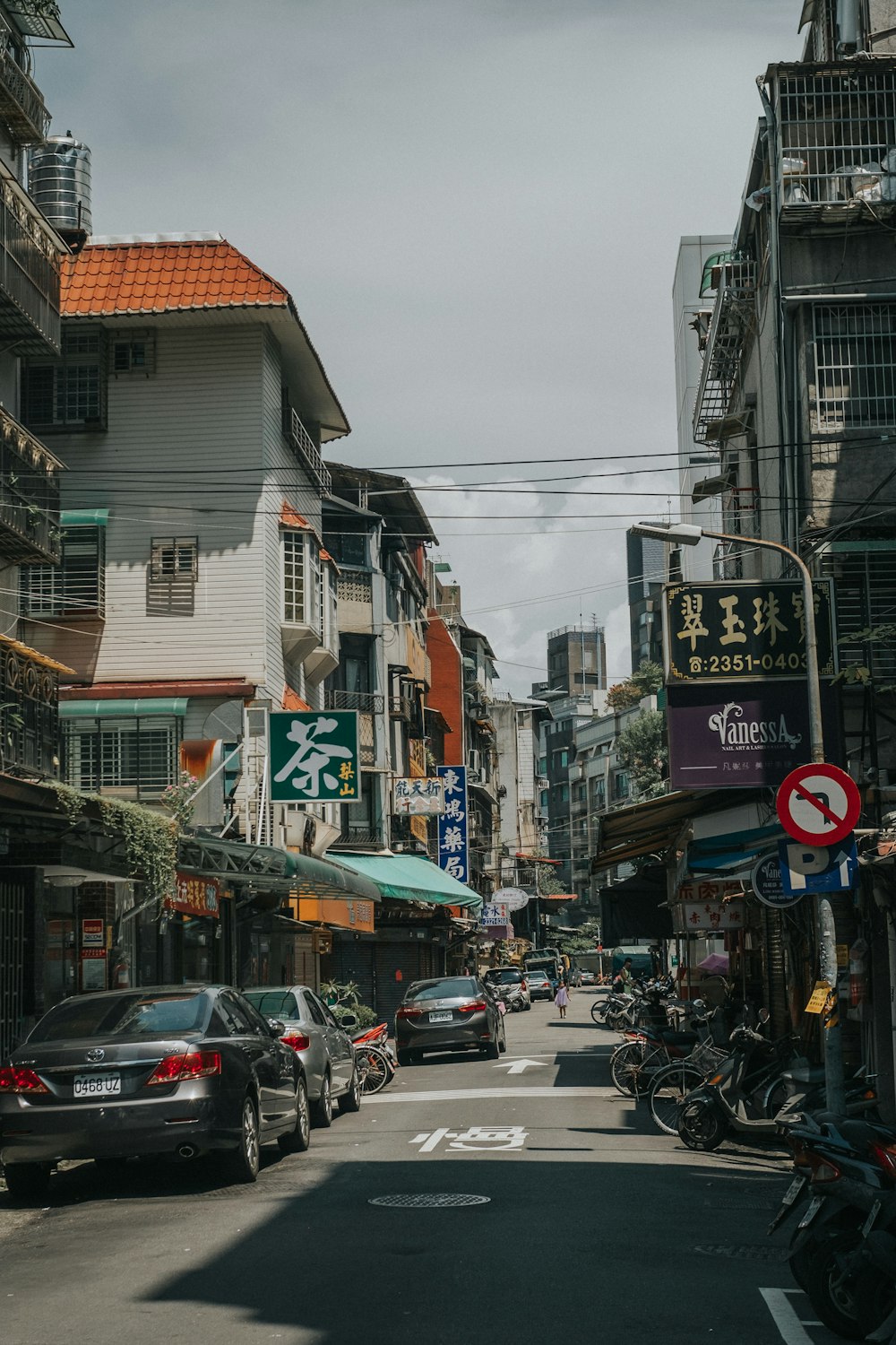 vehicles parked beside road between buildings