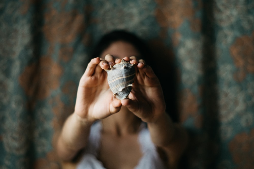 selective focus photography of woman showing conch shell