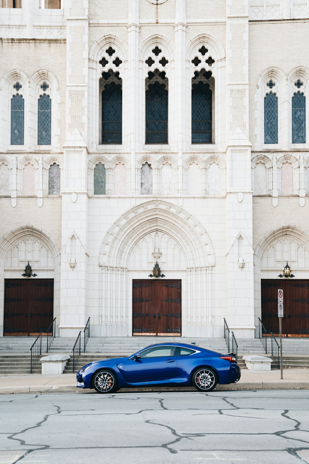 blue coupe parked in front of cathedral