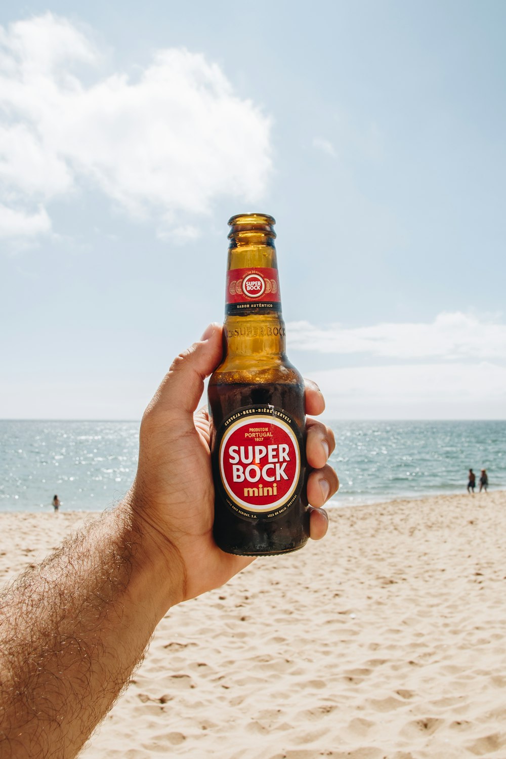 personne tenant une bouteille de Super Bock ouverte