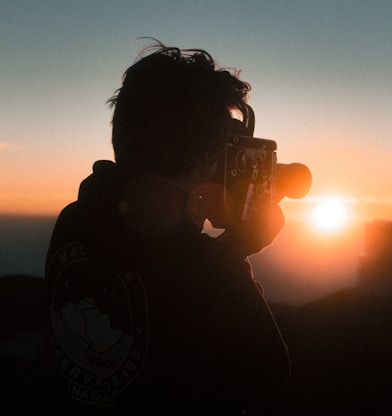 man holding classic camera during golden hour