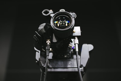 Close-up of a professional video camera lens reflecting studio lights.
