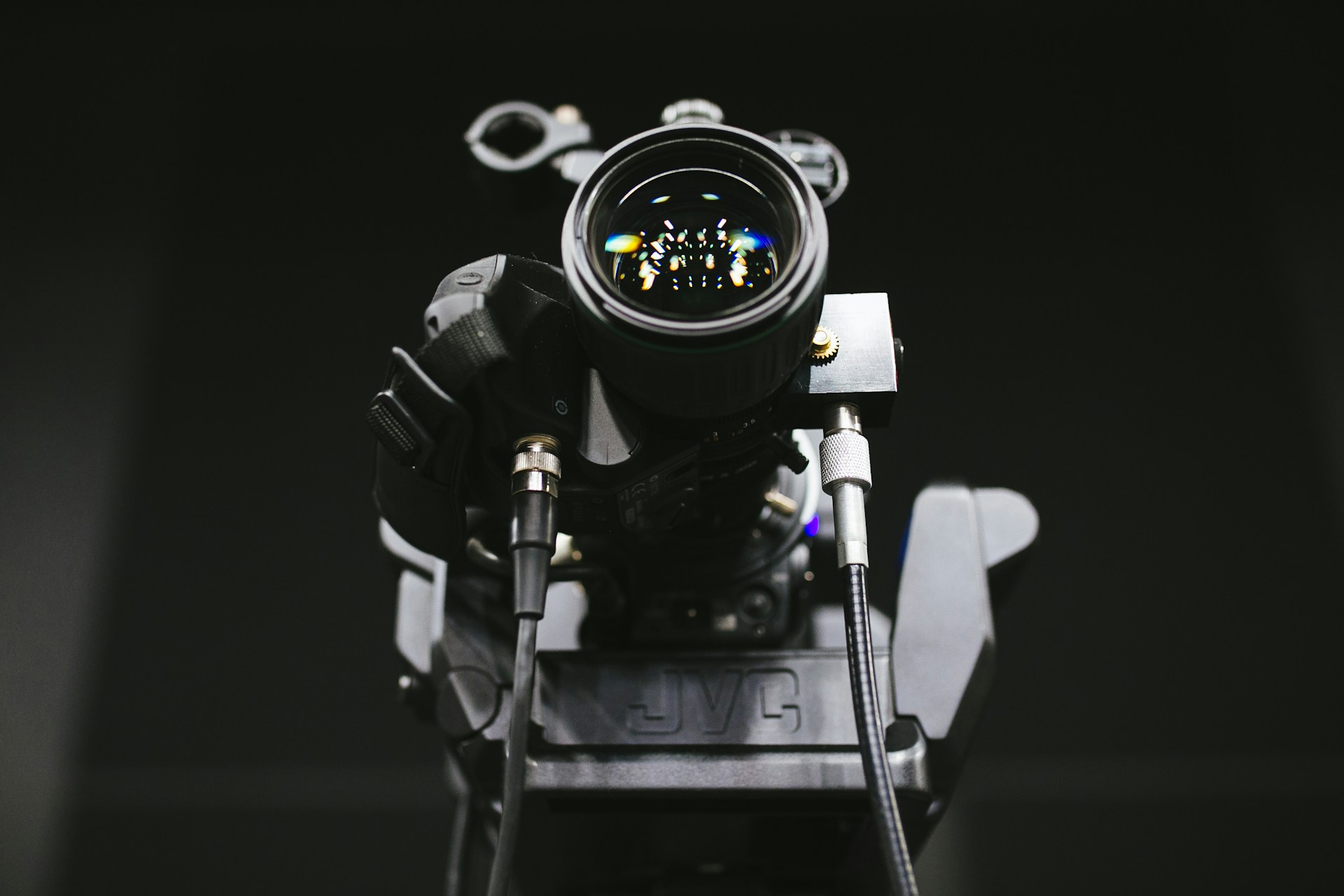 Close-up of a professional video camera lens reflecting vibrant studio lights in a modern media environment.