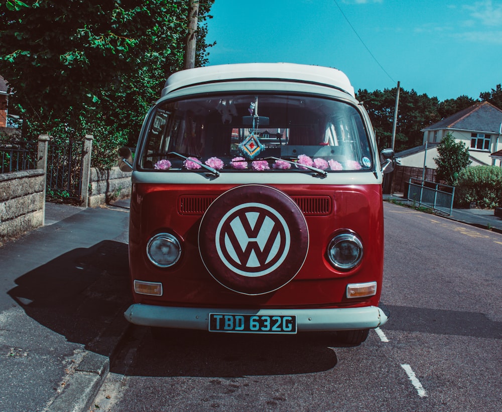 van hippie Volkswagen vermelha e branca estacionada perto do portão