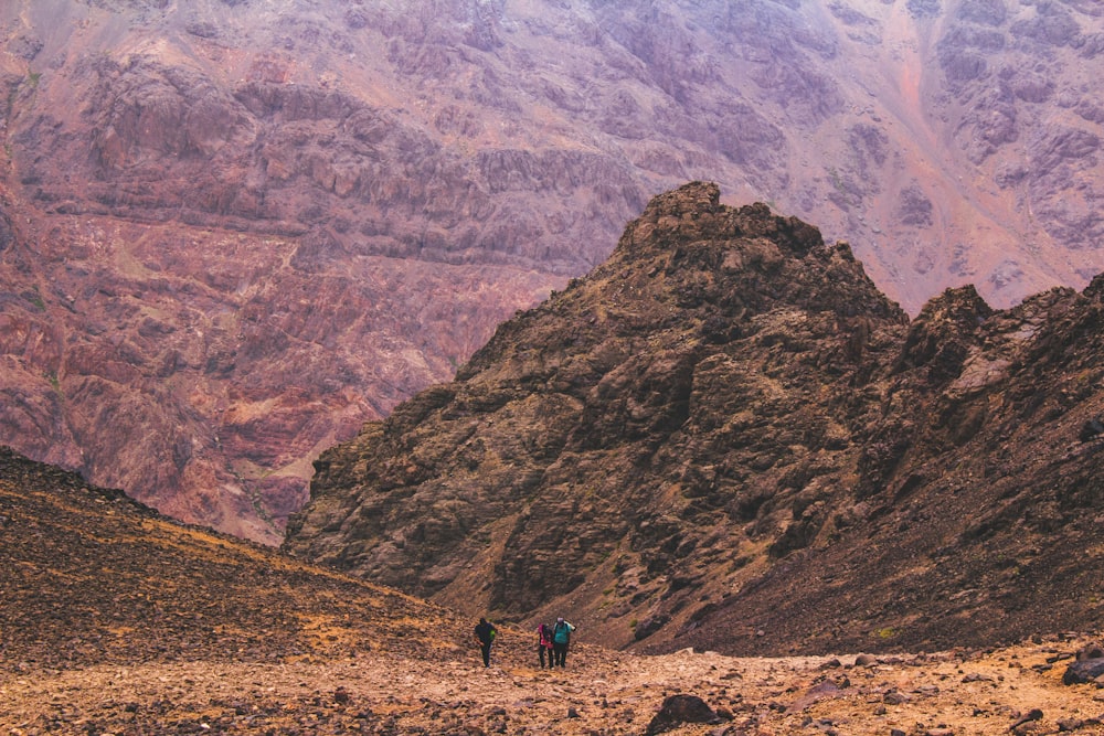 three person walking on hill