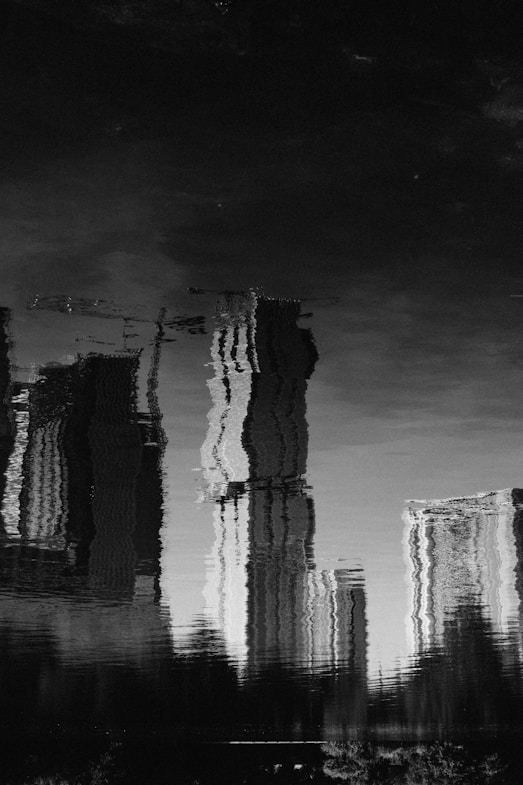 grayscale photo of reflection of buildings in water